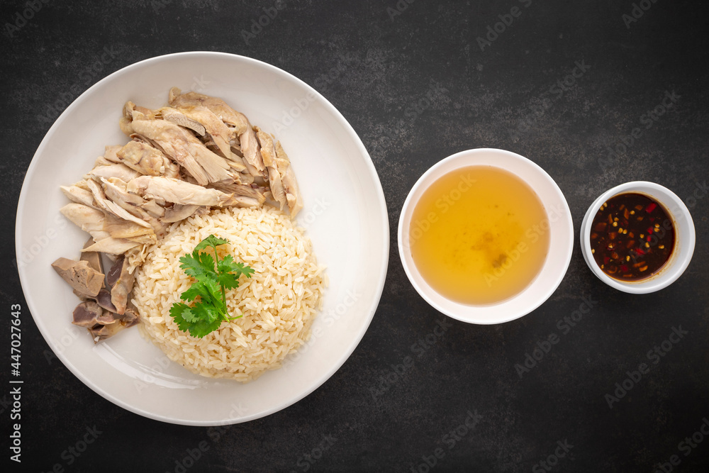 Khao Mun Gai, Thai food, rice steamed with chicken soup serve with chicken, soup and sauce on dark tone texture background, top view Khao Mun Gai, Thai food, rice steamed with chicken soup serve with chicken, soup and sauce on dark tone texture background, top view