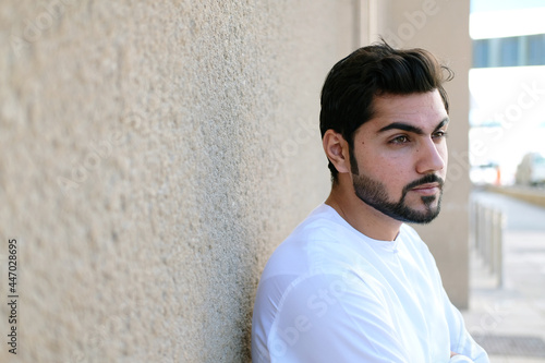 Young handsome Arab man posing wearing kandura. Close up portrait of Arabic boy with copy space background