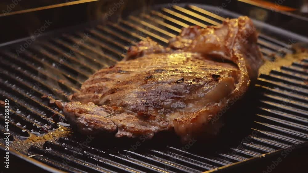 Roasting juicy meat steak with spices and herbs on a grill plate and smoke rised in slow motion. Healthy food concept. Roasting juicy meat steak with spices and herbs on a grill plate and smoke rised in slow motion. Healthy food concept.