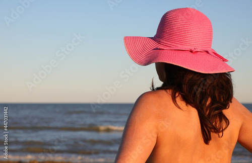 tanned woman in straw hat with long hair and seashore in summer
