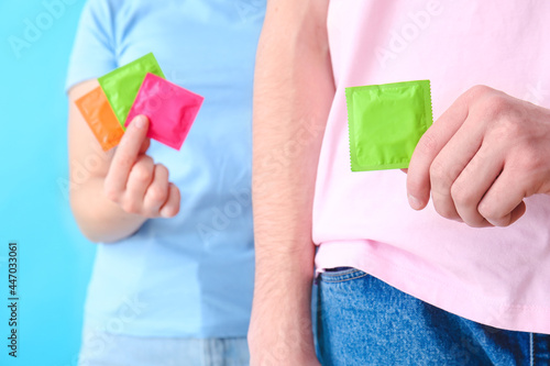 Couple with condoms on color background, closeup