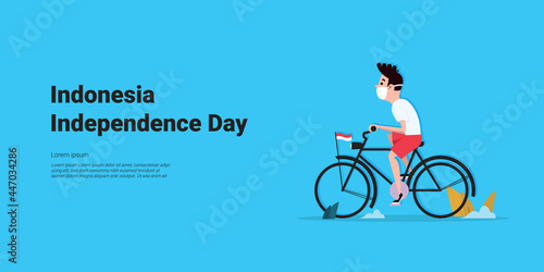 Little boy riding a bicycle and wearing a mask is leaving to celebrate Indonesia's independence day