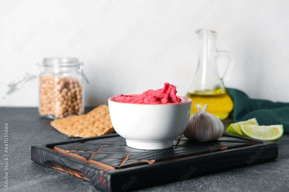 Bowl with tasty beet hummus and garlic on dark table, closeup Bowl with tasty beet hummus and garlic on dark table, closeup