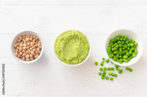 Bowls with tasty peas hummus and chickpeas on light wooden background