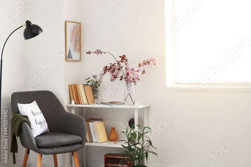 Book shelf with blossoming branches in interior of room