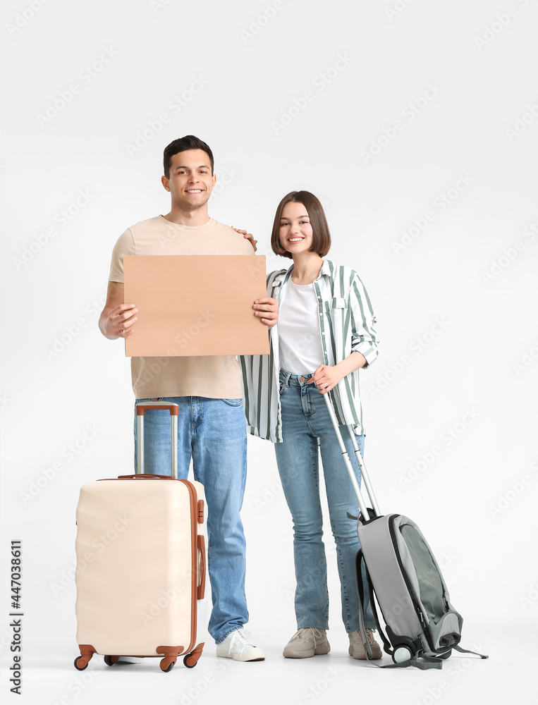 Young couple with cardboard and suitcases on light background Young couple with cardboard and suitcases on light background