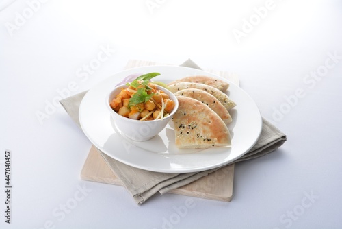 Indian vegetable bean curry with baked naan pizza bread in white background vegan dim sum Halal menu