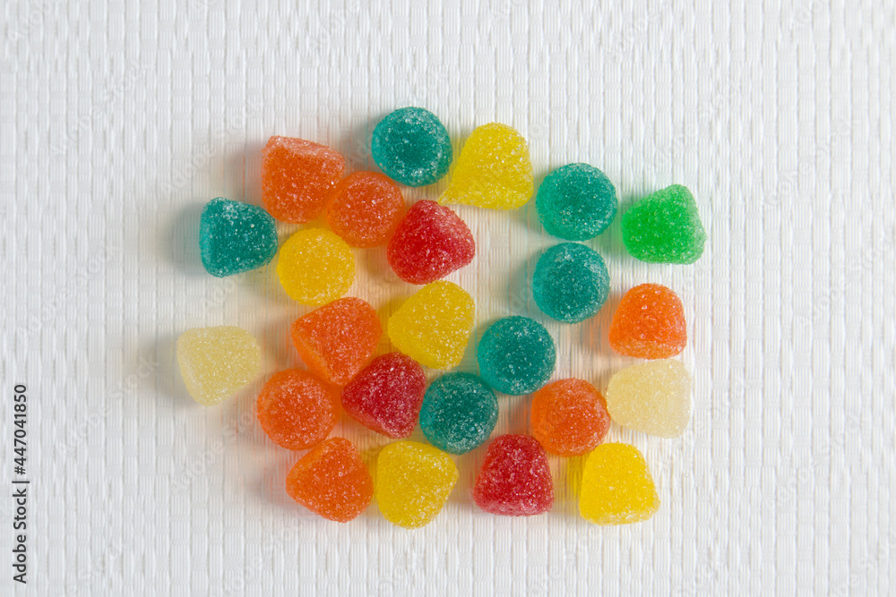 Bright colorful jelly candies in sugar on white textured background Bright colorful jelly candies in sugar on white textured background