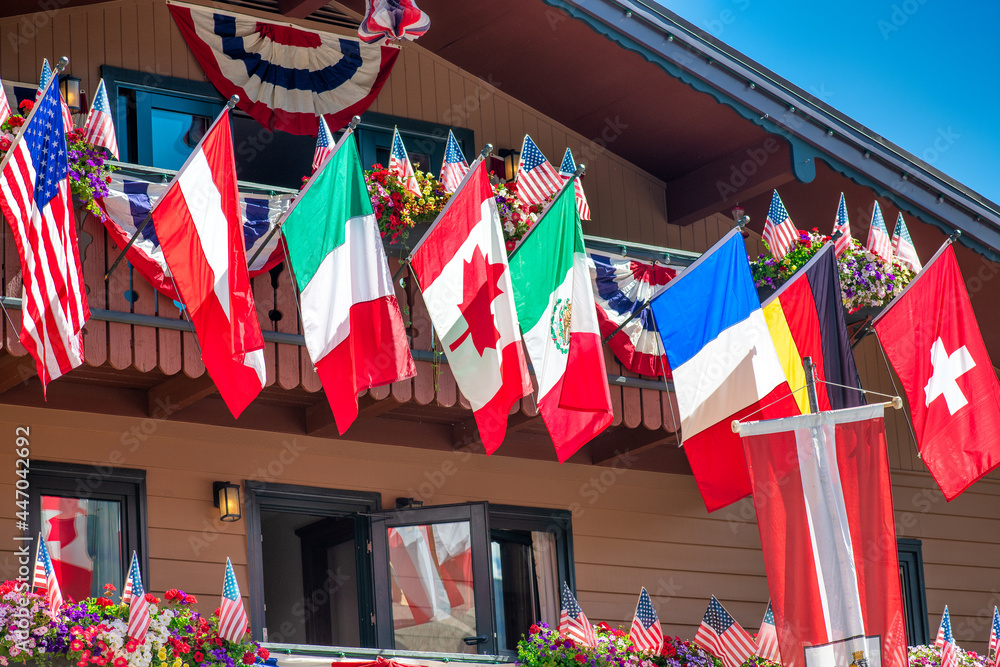 International flags waving at a wooden mountain house terrace.