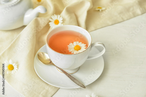 Cup of floral tea and flowers on light wooden background