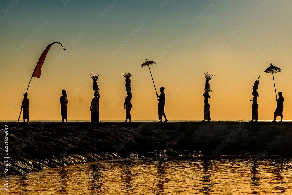 Φωτογραφία Silhouette group of people are marching on the beach with umbrella, flags and offerings when performing Hindu Bali morning beach ritual