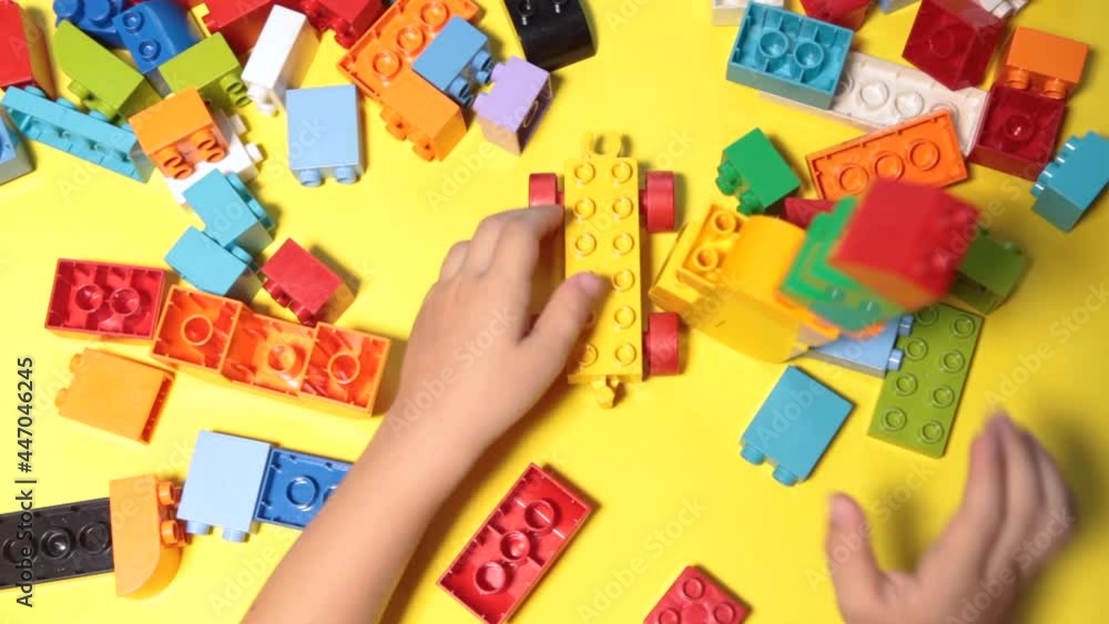 A beautiful boy is playing at home with building blocks. A cute smiling boy is playing with a blocks constructor with a lot of colorful plastic blocks in the room, building a city. Preschool classes. A beautiful boy is playing at home with building blocks. A cute smiling boy is playing with a blocks constructor with a lot of colorful plastic blocks in the room, building a city. Preschool classes.