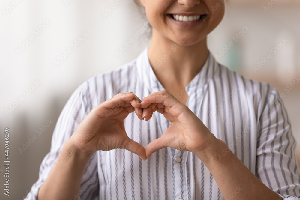 Φωτογραφία Close up cropped of smiling Indian woman showing heart shape gesture on chest, f
