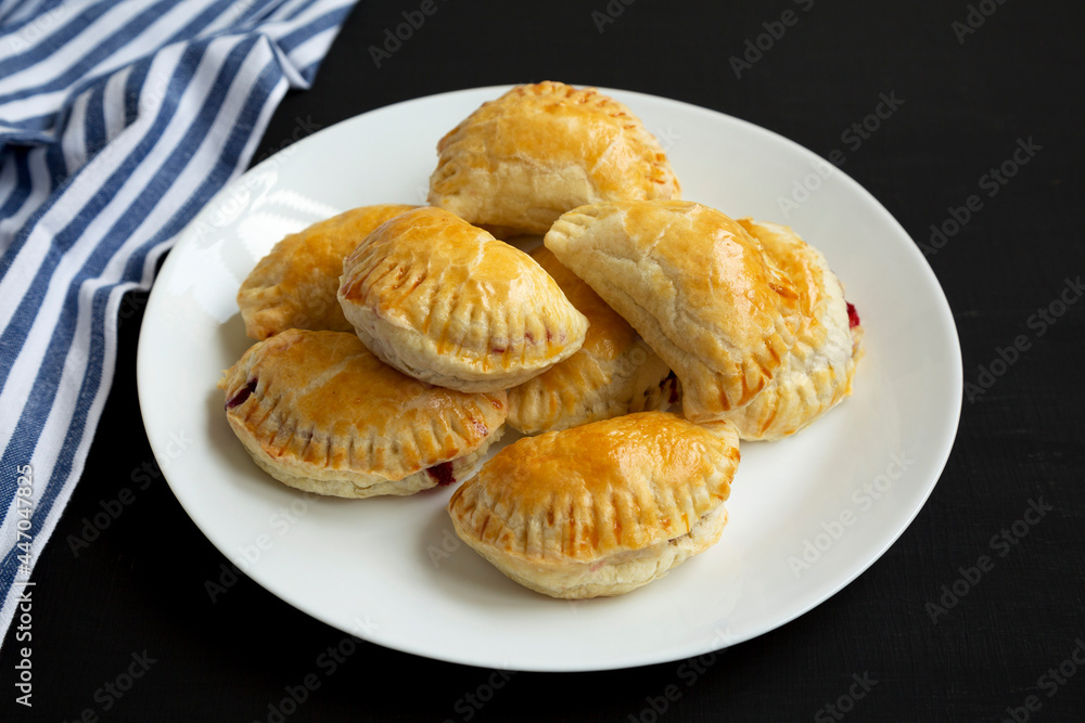 Homemade Cherry Hand Pies on a plate on a black surface, side view. Homemade Cherry Hand Pies on a plate on a black surface, side view.