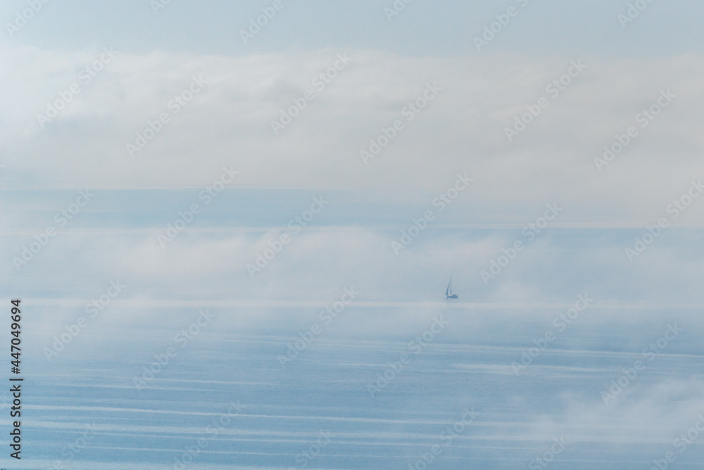 Sailboat sailing in the high seas covered in clouds and fog. Sailboat sailing in the high seas covered in clouds and fog.