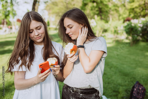 Two beautiful girls teenagers with bitten apples look into a smartphone. Healthy eating. Soft selective focus.