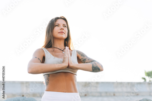 Young fit beautiful woman with long hair in white sport clothes practice yoga and meditation on the sea beach