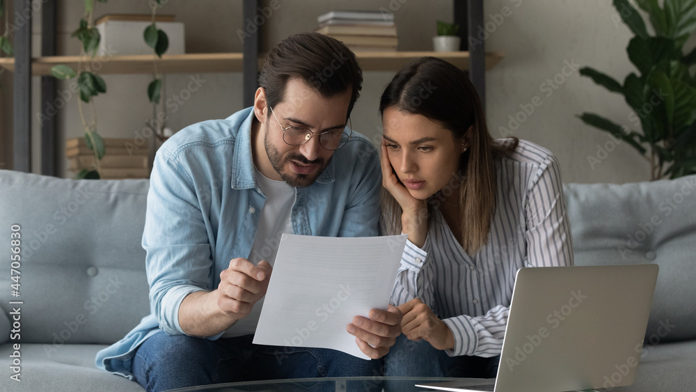 © fizkes - Serious pensive millennial 35s couple sit on sofa at home hold letter reading papers documents, learn details of contract, discuss agreement terms conditions, considering mortgage loan offer concept © fizkes - Serious pensive millennial 35s couple sit on sofa at home hold letter reading papers documents, learn details of contract, discuss agreement terms conditions, considering mortgage loan offer concept