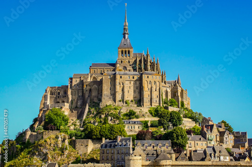 Mont Saint Michel with its spectacular houses, walls and monastery at the top, on a sunny day and blue sky.