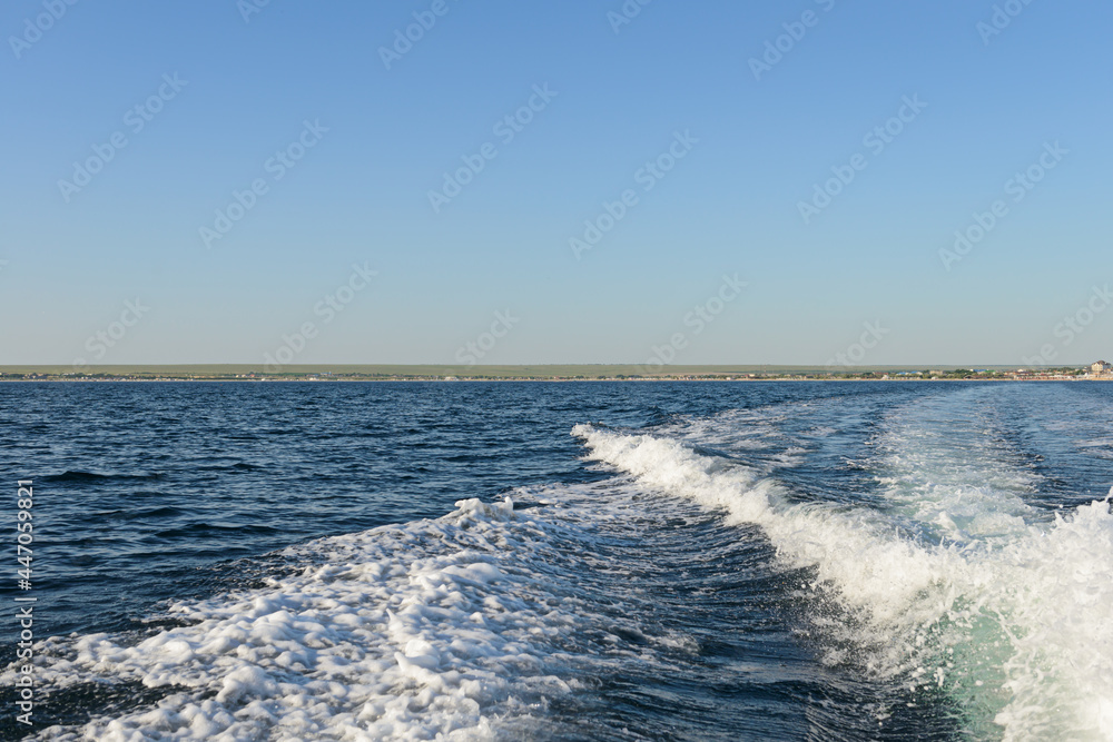 The wake of the boat on the surface of the sea on a summer day