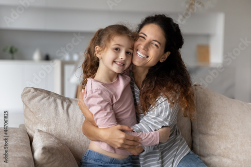 Portrait of smiling young Hispanic mother and teen daughter hug and cuddle show love and care. Happy Latin mom and small teenage girl child embrace enjoy family weekend at home. Gratitude concept.