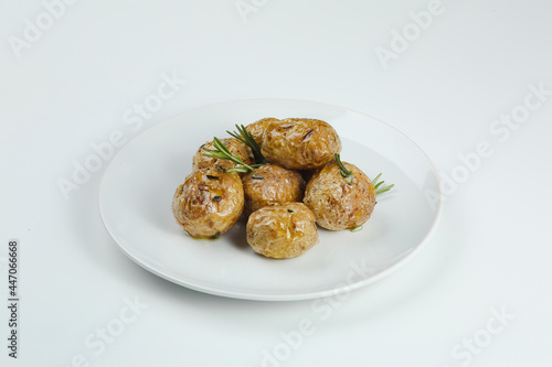 baked baby potatoe closeup on white plate. Roasted or baked baby potatoes with oil and herbs with white background