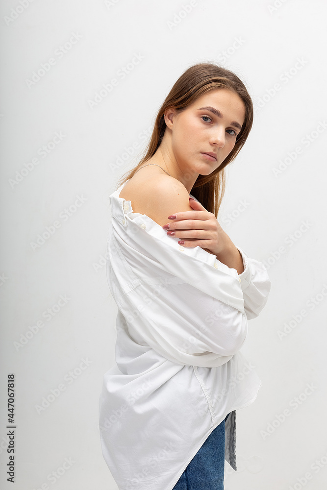 young attractive caucasian woman with long brown hair in shirt, blue jeans on white studio background. skinny pretty lady posing at bright room. portrait of beautiful female young attractive caucasian woman with long brown hair in shirt, blue jeans on white studio background. skinny pretty lady posing at bright room. portrait of beautiful female