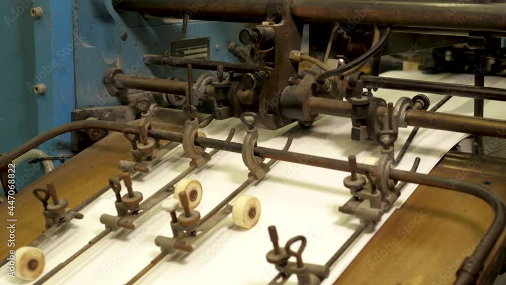 Machine in printing house folding papers with rollers on a conveyor belt Machine in printing house folding papers with rollers on a conveyor belt