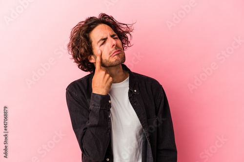 Young caucasian man isolated on pink bakcground crying  unhappy with something  agony and confusion concept.