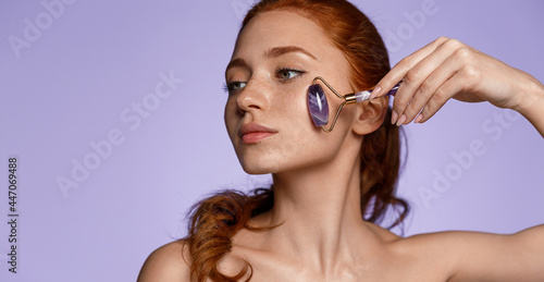 Tableau sur toile Sensual redhead girl massaging face-lift and skin rejuvenation at home with jade