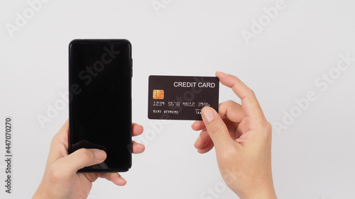 Hand is holding smart phone and black credit card on white background.