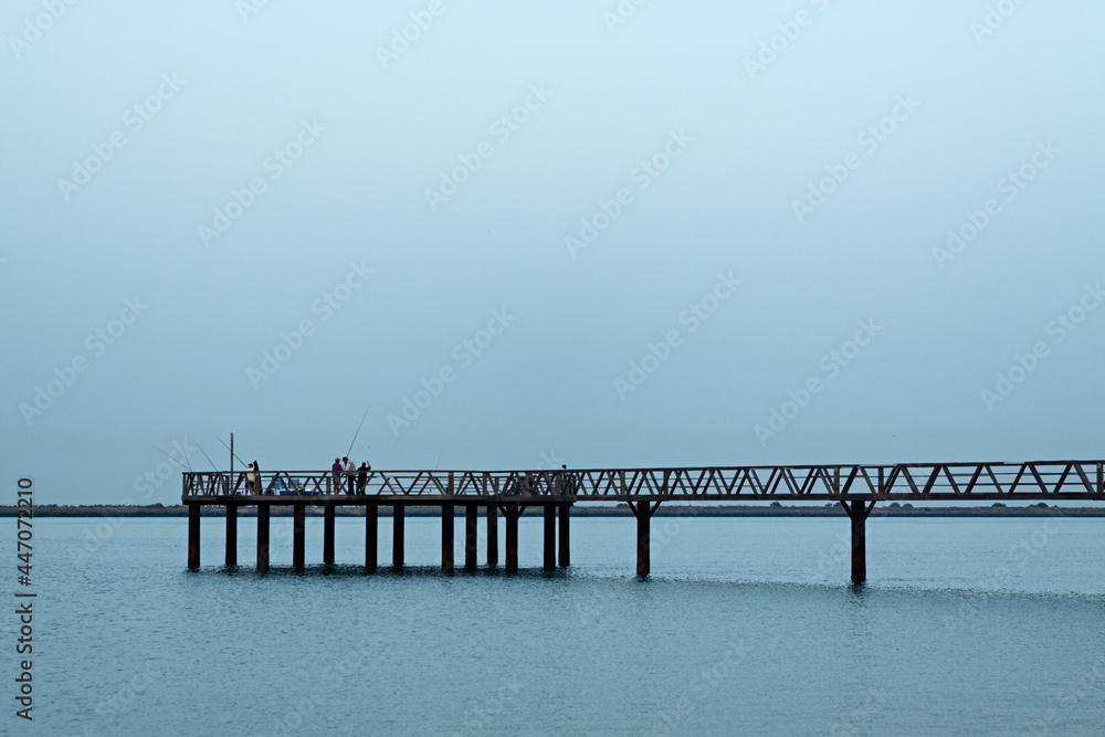 Pescadores en puente de madera en la playa de Mazagón, Huelva.