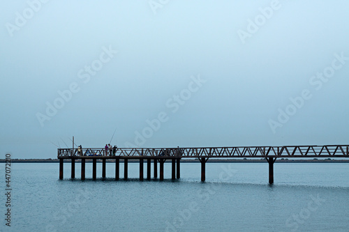 Pescadores en puente de madera en la playa de Mazag  n  Huelva.