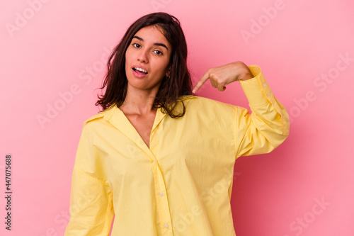 Young caucasian woman isolated on pink background person pointing by hand to a shirt copy space, proud and confident