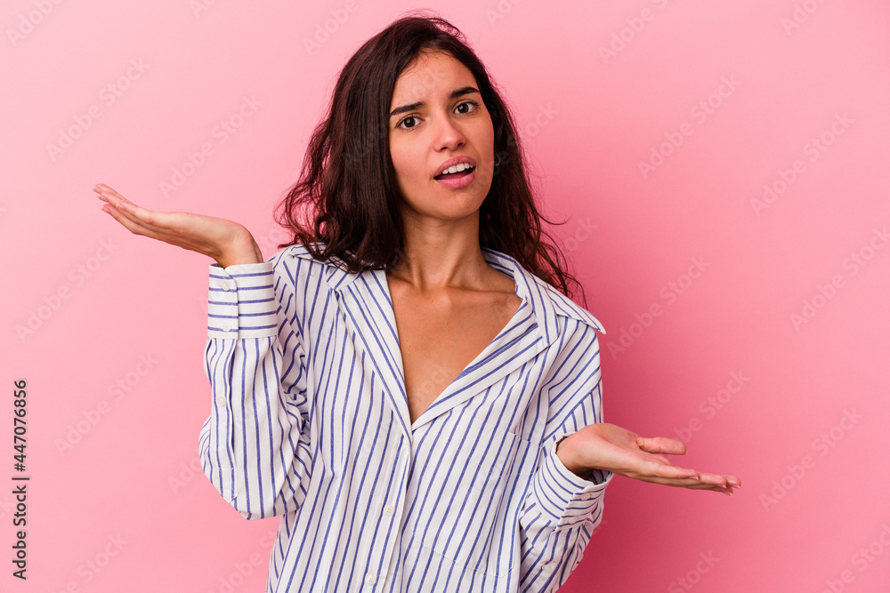 Young caucasian woman isolated on pink background confused and doubtful shrugging shoulders to hold a copy space. Young caucasian woman isolated on pink background confused and doubtful shrugging shoulders to hold a copy space.