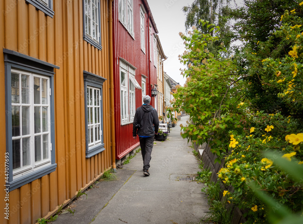 Tourist on narrow street with traditional colourful wooden houses in Trondheim