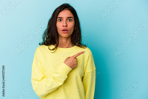 Young caucasian woman isolated on blue background pointing to the side