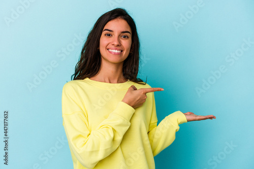 Young caucasian woman isolated on blue background excited holding a copy space on palm.
