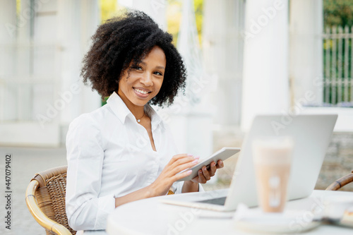 The student is studying online. The manager of Afro appearance works in a summer cafe on a computer. Prints a message to clients by email.
