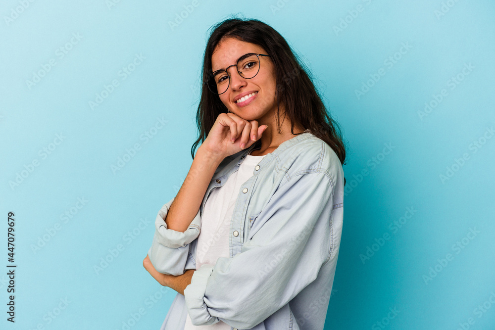 Young caucasian woman isolated on blue background smiling happy and confident, touching chin with hand. Young caucasian woman isolated on blue background smiling happy and confident, touching chin with hand.