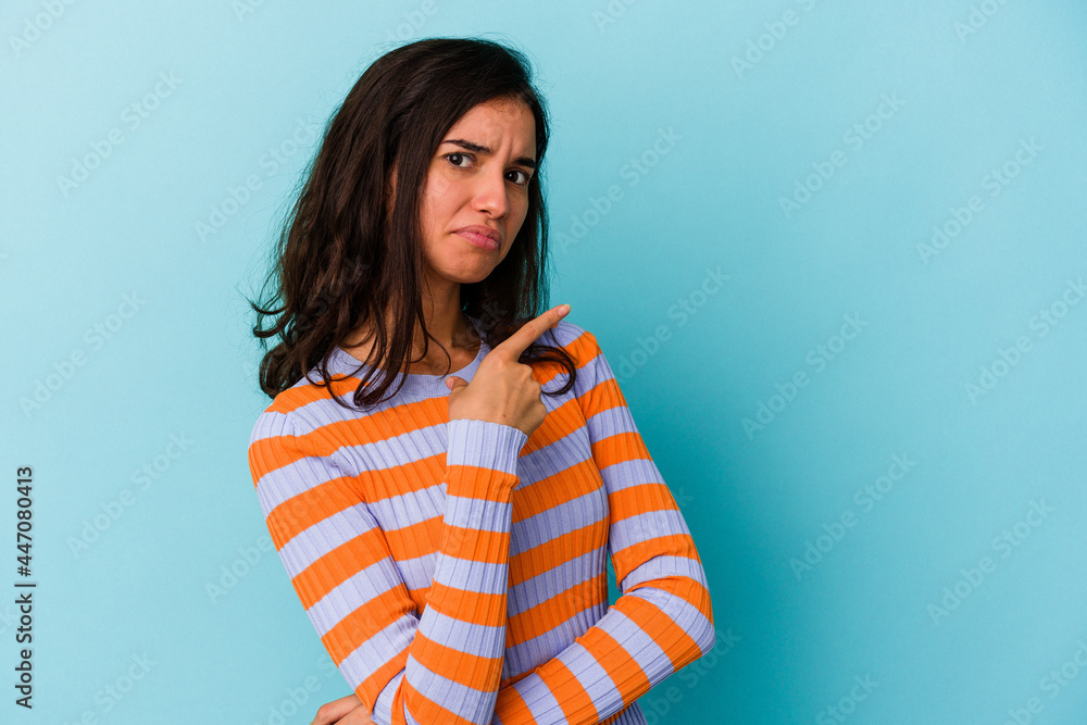 Young caucasian woman isolated on blue background smiling and pointing aside, showing something at blank space. Young caucasian woman isolated on blue background smiling and pointing aside, showing something at blank space.