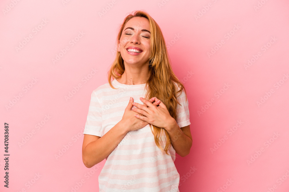 Caucasian blonde woman isolated on pink background laughing keeping hands on heart, concept of happiness. Caucasian blonde woman isolated on pink background laughing keeping hands on heart, concept of happiness.