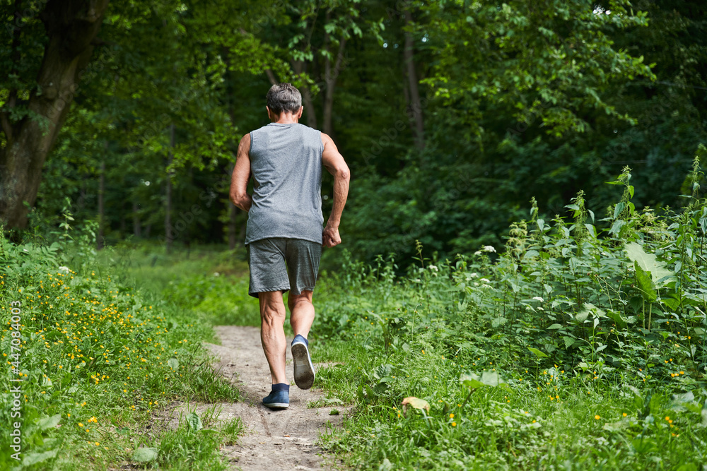 Man running with delight at the summer park and trying to keep body fit