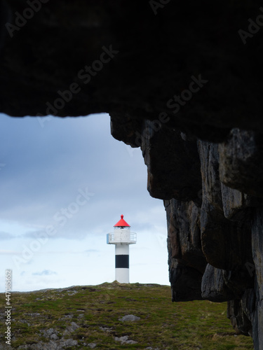 Lighthouse with rocks and cloudy sky