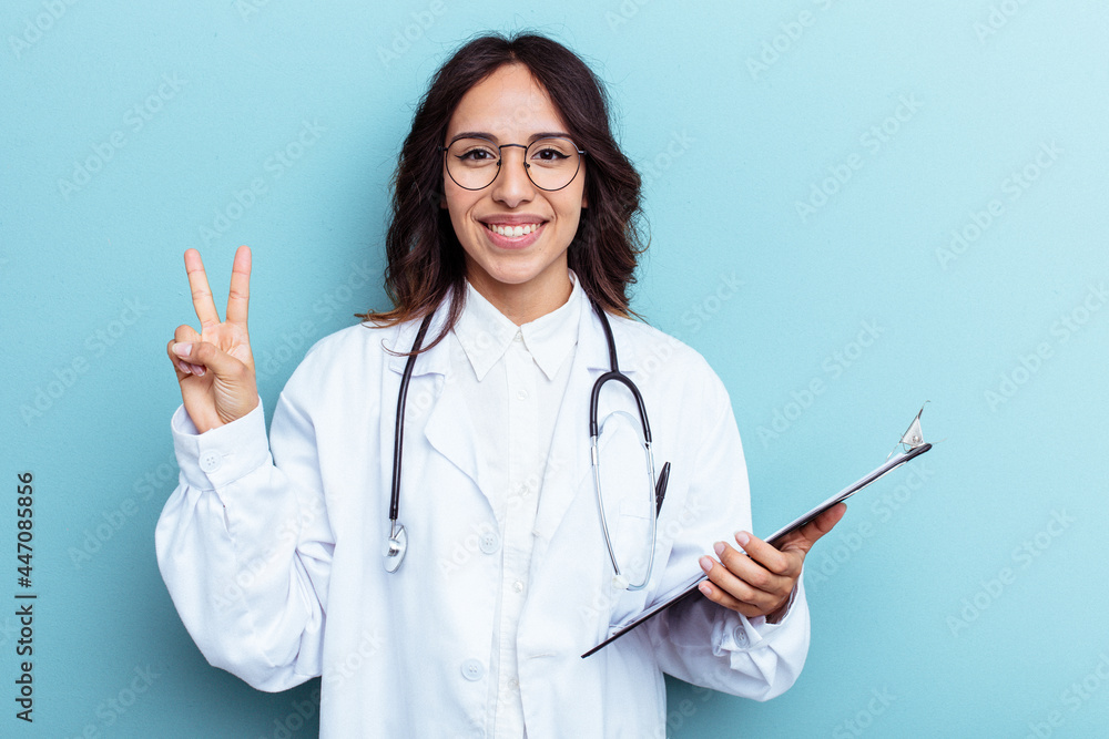 Young doctor mexican woman isolated on blue background showing number two with fingers. Young doctor mexican woman isolated on blue background showing number two with fingers.