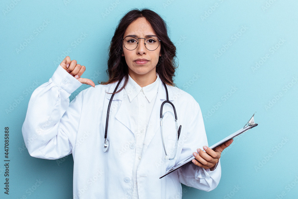 Young doctor mexican woman isolated on blue background showing a dislike gesture, thumbs down. Disagreement concept. Young doctor mexican woman isolated on blue background showing a dislike gesture, thumbs down. Disagreement concept.