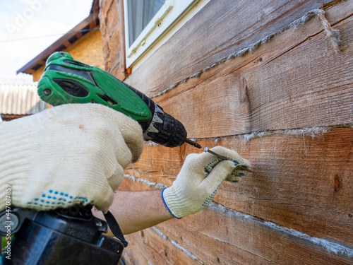 a beginner tries to use an electric screwdriver to screw a nail into the wall. Errors in the use of tools. Selective Focus
