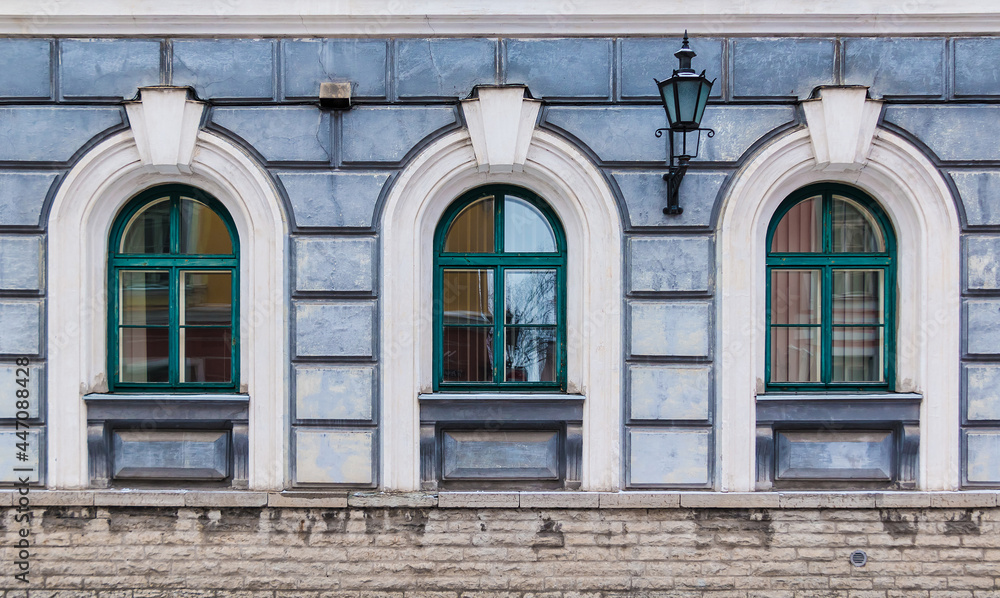 Three windows in a row on the facade of the urban historic building front view, Tallinn, Estonia
