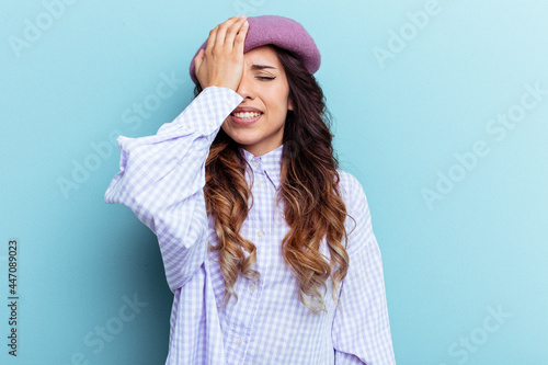 Young mexican woman isolated on blue background forgetting something, slapping forehead with palm and closing eyes.