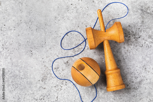 Classic wooden Kendama toy with blue threads on a concrete background with copy space, top view photo